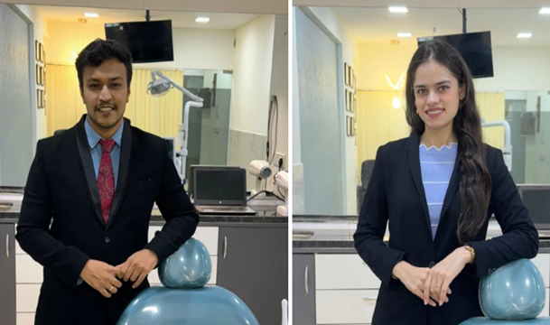 Picture3 - The Smile Connect Two professionals, a man and a woman, stand beside blue dental chairs in a clinic lobby or treatment room, both dressed in dark blazers.