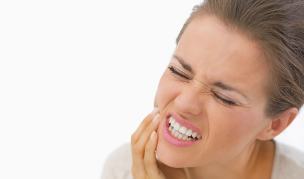 Woman grimacing in pain while holding her jaw, suggesting a toothache or dental discomfort on her right side.